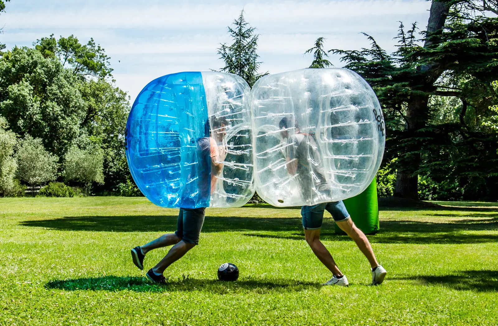 Deux joueurs de bubble foot qui se percutent dans un parc
